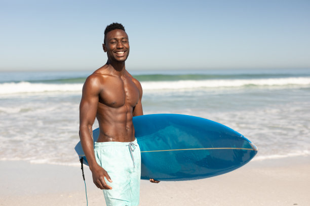 一个非裔美国人在海滩上拿着冲浪板图片下载