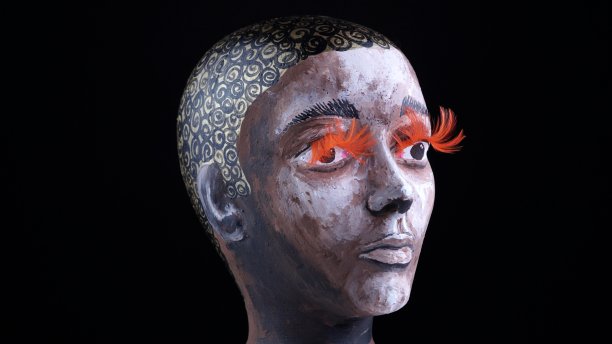 美丽的非洲女人的脸画的人体模型与棕色的眼睛和橙色的睫毛，在黑色的背景。乌木女模特护理治疗或化妆品广告概念构思，不是真人。图片下载