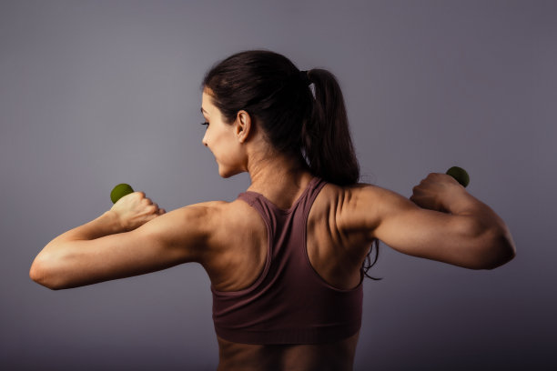 运动强壮健康快乐的女人训练与哑铃在运动顶部在紫罗兰的背景。特写肖像。后视图。这个概念图片下载