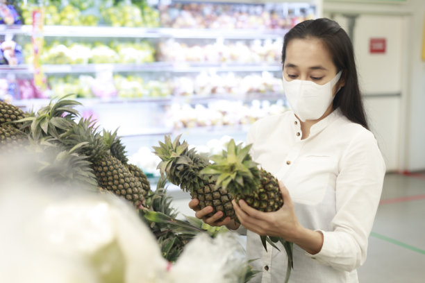 亚洲妇女长头发戴着保护面罩在超市百货公司。女性，在杂货店买水果。新冠肺炎疫情后的新常态。家庭的概念。软焦点的照片。图片下载