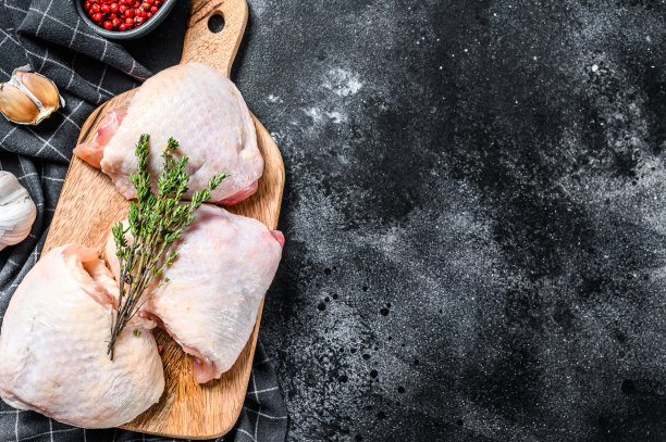 新鲜鸡腿带皮放在砧板上，有机肉。黑色背景。前视图。本空间图片下载