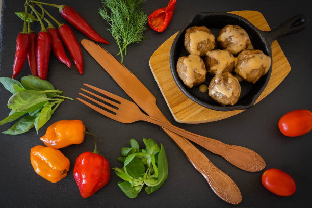 木架上的小煎锅，配上法式酱汁的肉丸子，装饰有旧餐具、蔬菜和香草图片下载
