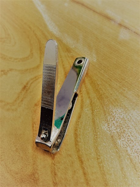 一个钢制的钉切割器，放置在一个木制的桌面上。图片下载