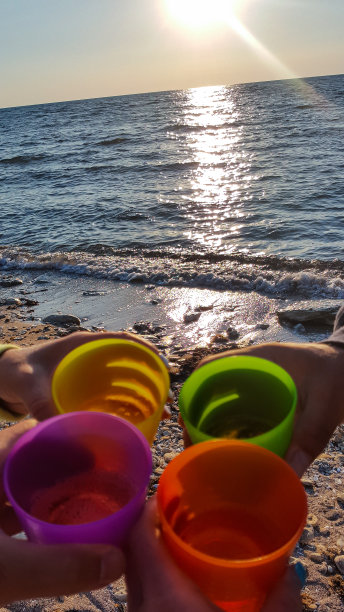 以大海为背景的四只玻璃杯。海面上落日的倒影图片下载