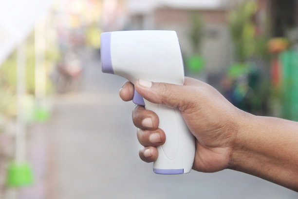 一个男人的手拿着一个数字体温检测设备图片下载