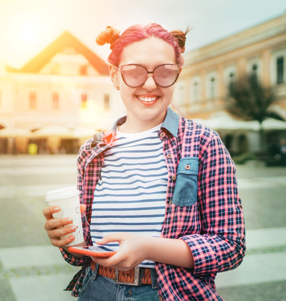 美丽的现代年轻女性青少年肖像与非凡的发型，格子衬衫，“咖啡带走”的帽子和苗条的智能手机。现代青少年或开朗的学生概念形象。图片下载