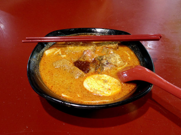 一碗新加坡Laksa Yong Tau Foo，这是当地一种很受欢迎的菜肴，用辛辣的咖喱肉汁和椰奶搭配;鱼酱豆腐茄子;蔬菜;面条下面是墨鱼和鱼丸。图片下载