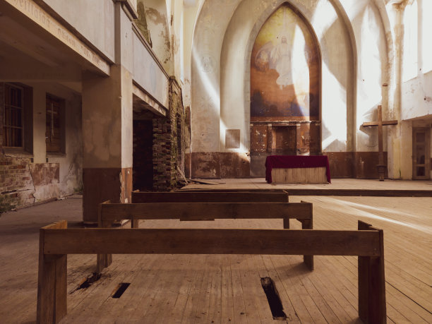 废弃教堂里的长凳和祭坛。宗教建筑的古老内部。十字站在角落里图片下载