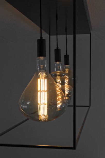 一个黑色金属框架的天花板灯在夜间的特写，抱着3个大尺寸的装饰灯泡与一个金色的完成和螺旋灯丝LED的图片下载