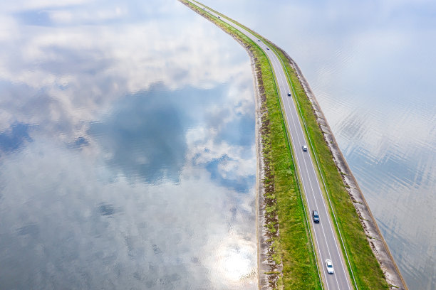 在夏天，湖上的山脊上有道路和汽车交通。航拍照片图片下载