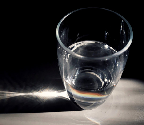 一杯白水和分散的多色光。图片下载