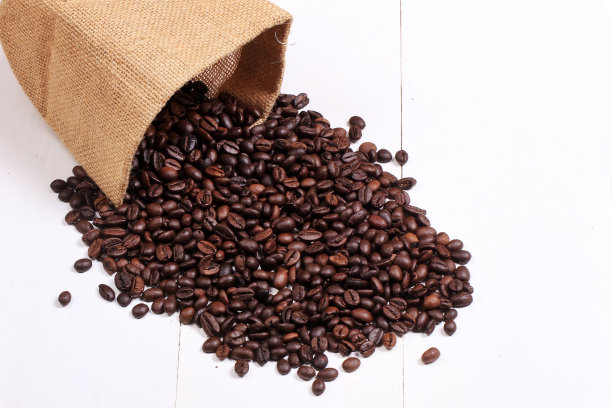烘好的咖啡豆撒在粗麻袋上孤立白色图片下载