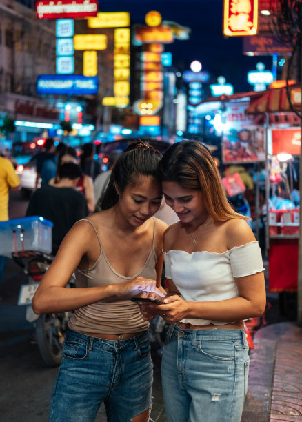 两个女孩晚上在城市里用手机库存照片图片下载