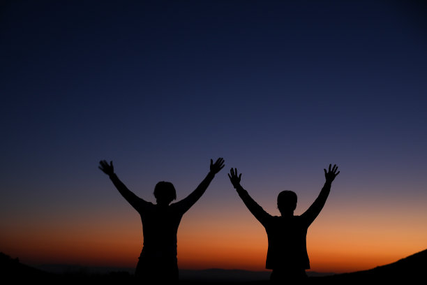 两个女人举起双手庆祝日出的剪影图片下载