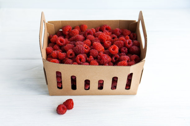 白色桌子上的盒子里装着新鲜的覆盆子图片下载