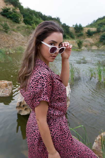 年轻美丽的时尚模特白种人黑发女人与复古太阳镜和夏季连衣裙摆姿势在自然靠近湖。户外时尚照片美丽的波希米亚女士在河边图片下载