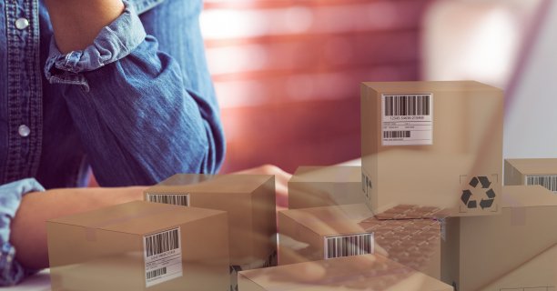 一个白人女人用笔记本电脑在网上购物旁边放着一堆盒子。图片下载