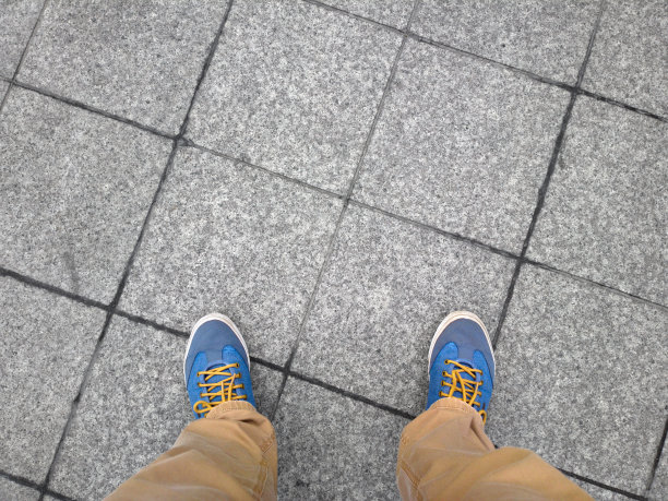 一个男人的脚踩在水泥砖上。图片下载