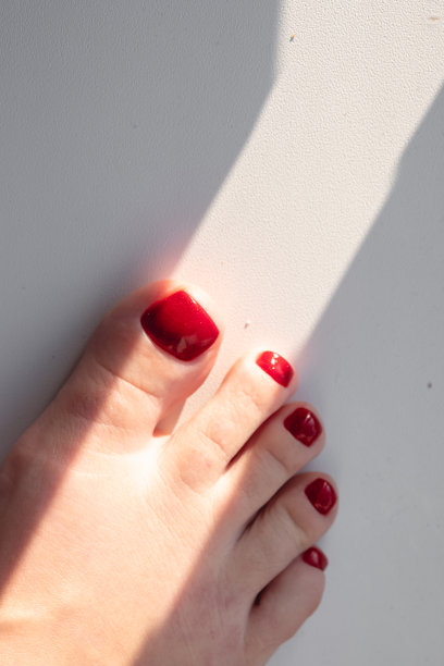 近距离的照片，一个美丽的女性脚与红色足疗在白色的背景。红色的指甲油图片下载