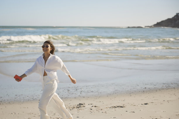 穿着白色衣服的美女在沙滩上跑步图片下载