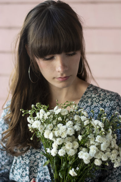 美丽的白人女孩在粉红色的墙拿着白色的花图片下载