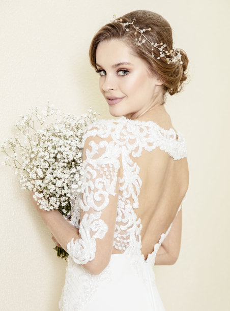 美丽的新娘穿着婚纱站在墙前图片下载