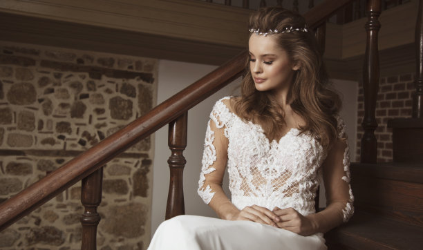 美丽的新娘穿着婚纱坐在木楼梯上图片下载