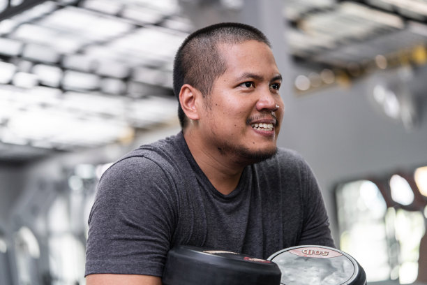 一名亚洲男子在健身房锻炼时看着镜子图片下载