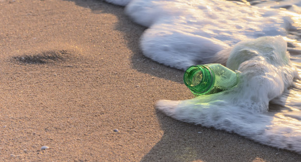 海边的塑料瓶在海浪的泡沫中。海洋污染的概念。环境保护。本空间图片下载