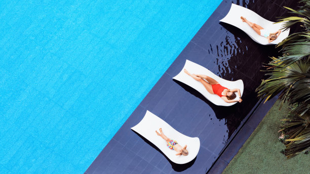 年轻的母亲，孩子们在游泳池的日光浴床上休息图片下载