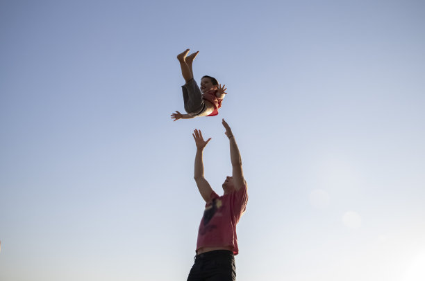 一位慈爱的父亲将儿子抛向空中，接住他。孩子笑着相信爸爸。爱父母和照顾孩子的生活方式。父爱和游戏的概念。图片下载