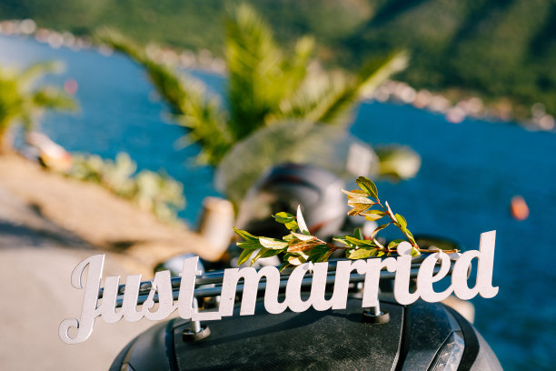 刚结婚的字母在摩托车后备箱。白色木制信件。黑山，佩拉斯特，一辆停在海滨的摩托车。欧洲蜜月旅行的概念。图片下载