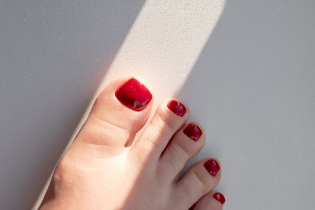 近距离的照片，一个美丽的女性脚与红色足疗在白色的背景。红色的指甲油图片下载