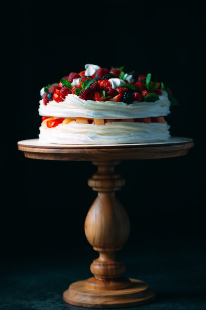 水果蛋糕。用浆果装饰的蛋糕，放在黑色背景的木架上。图片下载