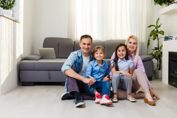 快乐的一家人玩进新家。爸爸，妈妈和孩子在一起玩。搬家日和房地产概念图片下载