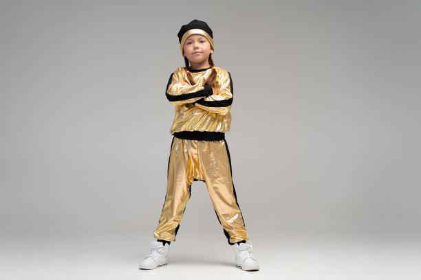 快乐的小女孩在金色套装跳舞孤立在白色的背景。图片下载