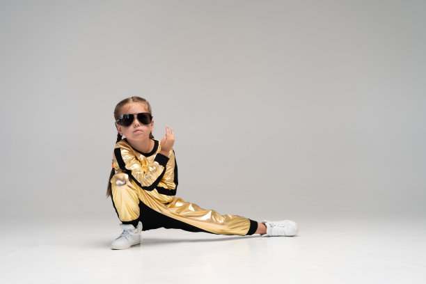 快乐的小女孩在金色套装跳舞孤立在白色的背景。图片下载