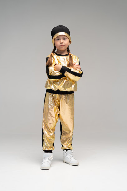 快乐的小女孩在金色套装跳舞孤立在白色的背景。图片下载