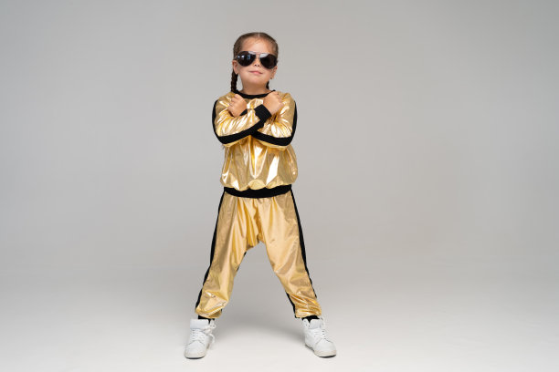 快乐的小女孩在金色套装跳舞孤立在白色的背景。图片下载