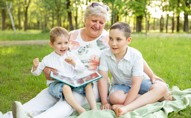 孩子们和奶奶玩得很开心。年长的妇女展示家庭相册图片下载
