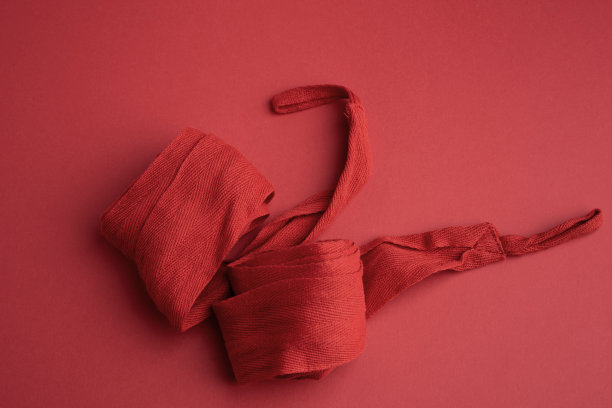 一双红色纺织绷带，用于运动员在红色背景上进行运动训练前缠绕双手图片下载