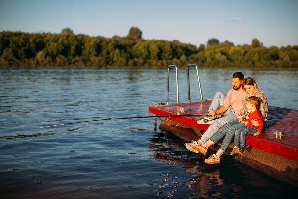 快乐的家庭在河边或湖边的码头钓鱼在夏天的时间。为广告或博客拍摄有关家庭和旅行的照片图片下载