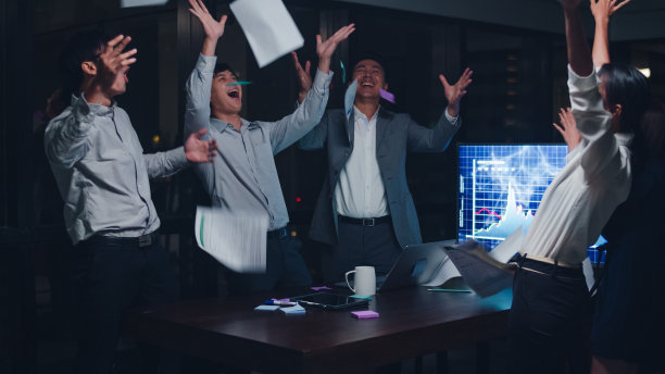 一群年轻的商人亚洲商人和女商人在小型现代化的夜间办公室的会议室里扔着文件，感受着成功后的成功感。图片下载