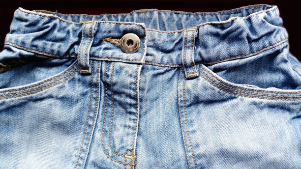 蓝色的牛仔裤。棉质地粗料。一块天然靛蓝破布的碎片。垂直的皱纹，深色和浅色的线，单独的缝线是显而易见的。图片下载