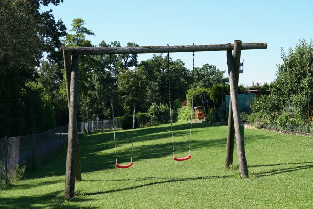 在阳光明媚的夏日里，在瑞士最大的村庄和城镇附近的花园中，为孩子们准备的带有红色座椅的木制秋千。图片下载