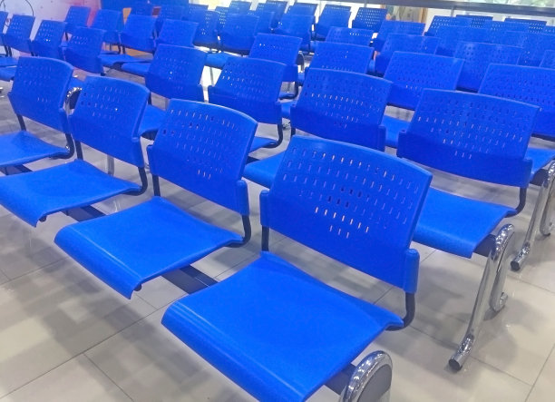 在一个房间里，蓝色的玻璃纤维椅子放在干净的灰色瓷砖地板上图片下载