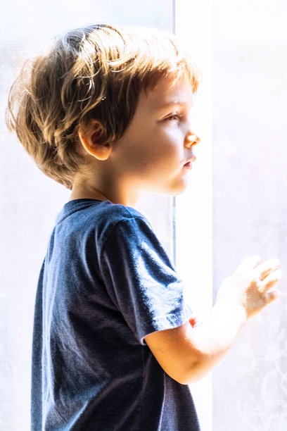 一个沉思的小男孩望着窗外图片下载