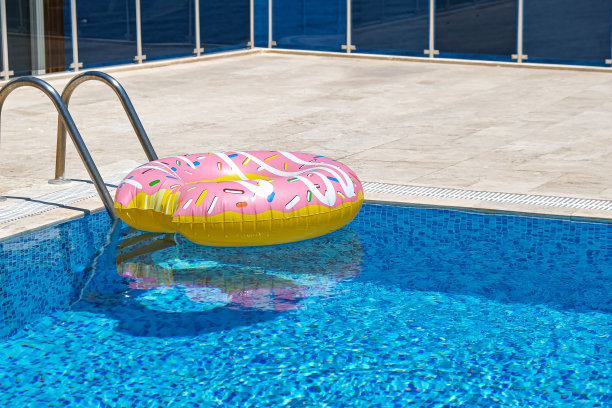 粉色充气甜甜圈漂浮在游泳池床垫。沙滩泳池配件。暑假的概念图片下载