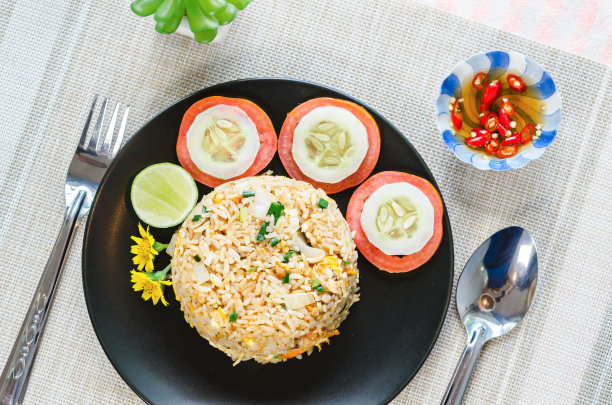 桌布上的黑色盘子里的炒饭和蔬菜。图片下载
