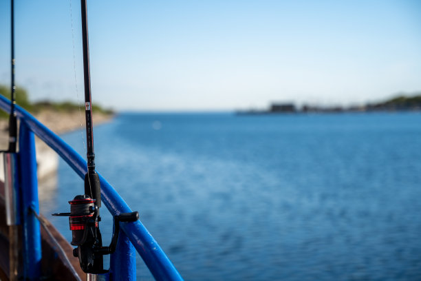 一个背光特写照片的蓝色轨道和一艘船上的钓竿。背景是清澈的蓝天和蓝色的海洋图片下载